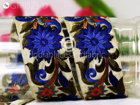 two decorative fabric pieces with intricate floral designs, including blue and red flowers, placed on a surface.