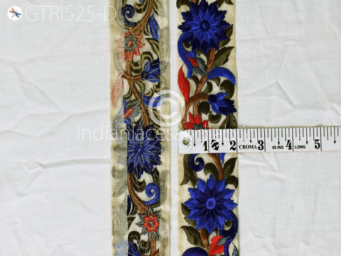 two pieces of fabric with intricate floral designs, including blue and red flowers, and a ruler for size comparison.