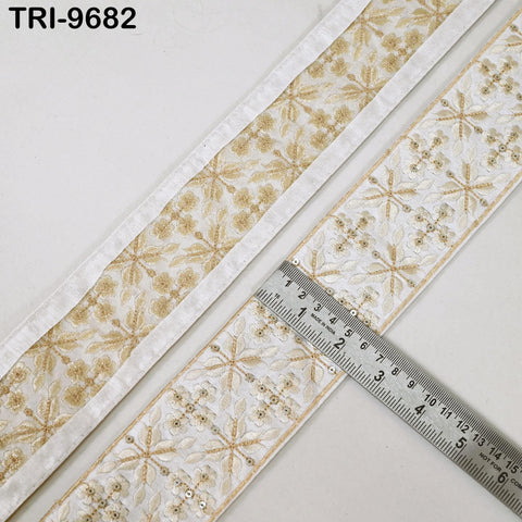 two pieces of fabric with a floral pattern, one with a white border and the other with a gold border. A ruler is placed on top of the fabric, indicating the size of the fabric.