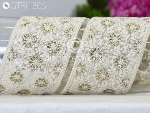 two pieces of white lace fabric with gold floral designs, placed on a white surface.