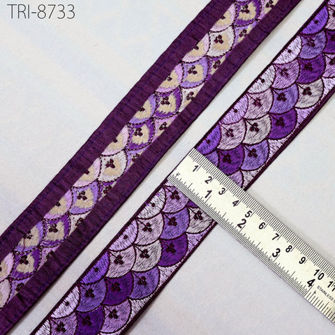 a close-up view of a decorative purple and white fabric with a repeating pattern of scales or waves. A ruler is placed next to the fabric, indicating its size or dimensions.