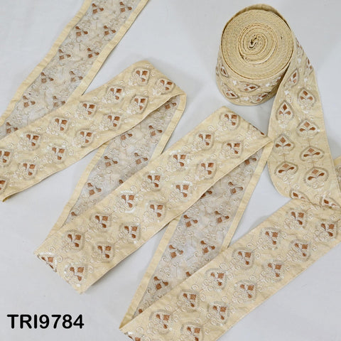 a collection of beige fabric with a repeating pattern of small white flowers or leaves. The fabric appears to be a decorative material, possibly used for sewing or textile art.