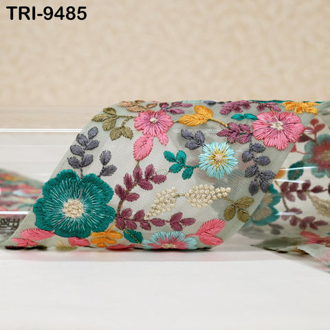 a close-up view of a fabric with a vibrant floral pattern, including various shades of pink, green, blue, and yellow flowers and leaves.