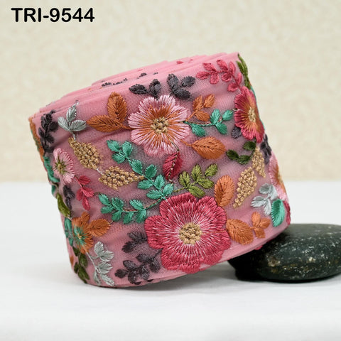 a pink fabric with a floral design, including various flowers and leaves, arranged in a decorative manner.