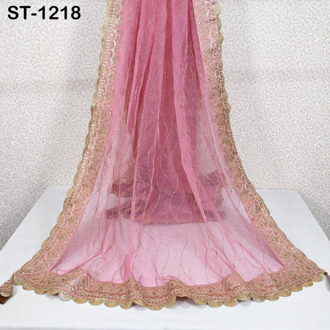 a pink and gold decorative fabric draped over a white surface, with a gold border and intricate embroidery.