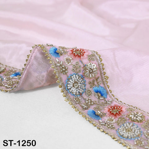 a close-up view of a delicate, intricately embroidered fabric with a pink background. The fabric has a floral pattern and is adorned with small, colorful beads and sequins. The image is a close-up of the fabric, focusing on the details of the embroidery.