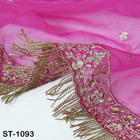 a close-up view of a pink fabric with intricate gold embroidery and fringe details.