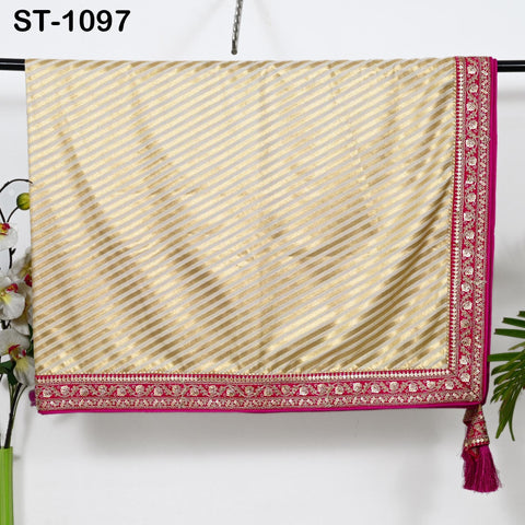 a gold and pink striped fabric with a decorative border, hanging on a hanger.
