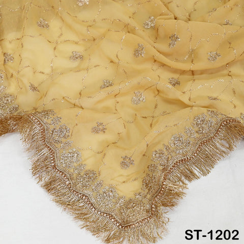a close-up view of a yellow fabric with intricate gold embroidery and fringe details. The fabric appears to be a piece of clothing or textile with a decorative design.