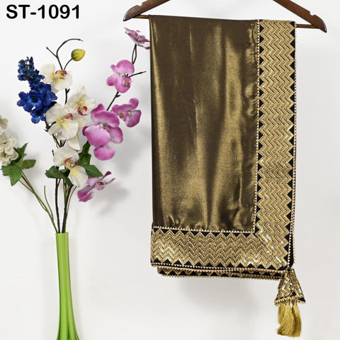 a gold-colored fabric with a decorative border, hanging on a wooden hanger next to a vase filled with colorful flowers.