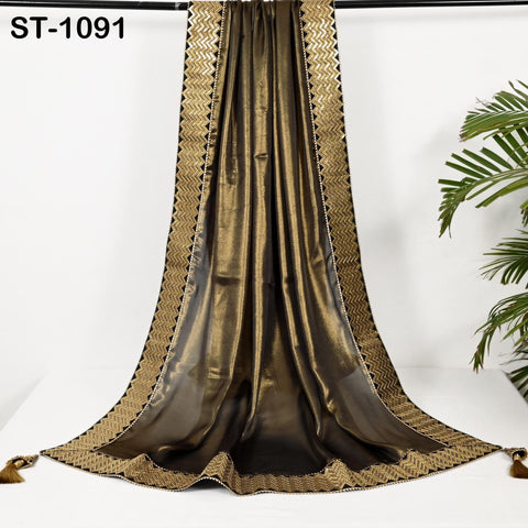 a long, shiny, gold-colored fabric draped over a white surface, with a decorative border around the edges.