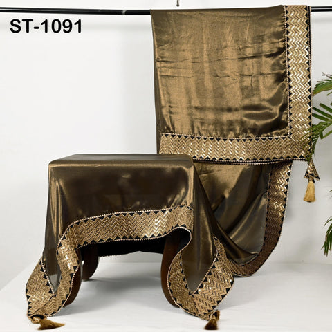 a brown satin tablecloth with gold trim and tassels, hanging on a white background.