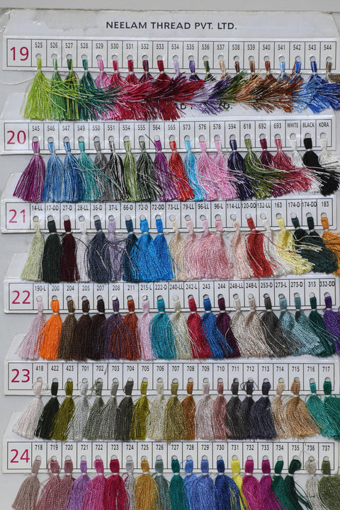 a collection of colorful spools of thread arranged in rows and columns, with each row representing a different color and each column representing a different type of thread. The spools are labeled with numbers and text, indicating the color and type of thread they contain.