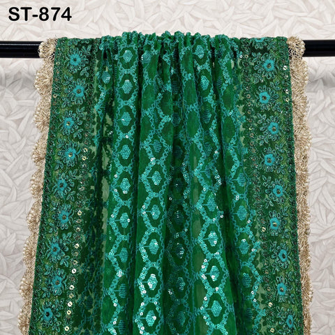 a green and gold sequined fabric draped over a black rod.
