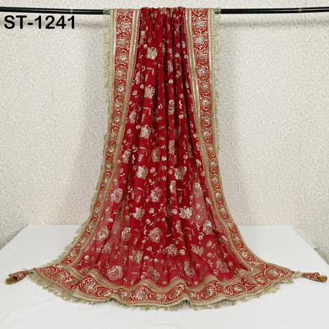 a red and gold embroidered shawl hanging on a black rod.