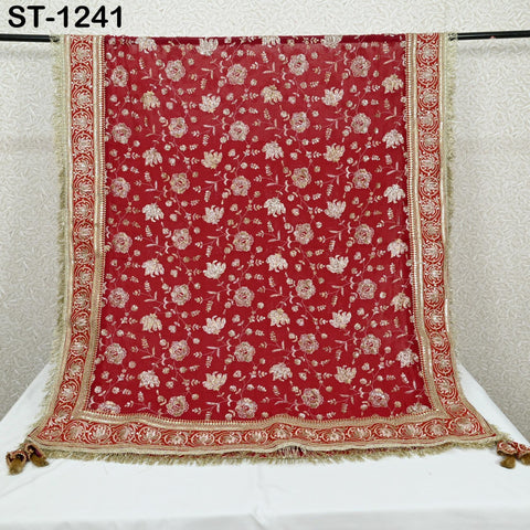 a red and gold embroidered shawl with a floral pattern, hanging on a rack.