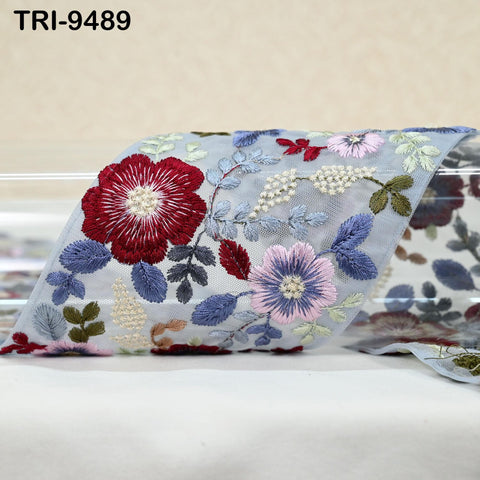 a close-up view of a decorative fabric with a floral pattern. The fabric is adorned with various colorful flowers and leaves, creating a visually appealing and intricate design.