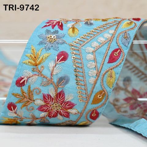 a close-up view of a vibrant, intricately embroidered fabric with a floral pattern in shades of blue, red, and yellow.
