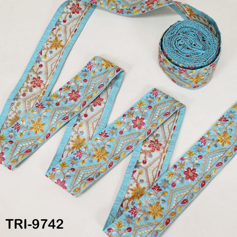 a collection of decorative fabric pieces, including a blue and white floral patterned fabric and a rolled-up blue fabric with a similar floral pattern.