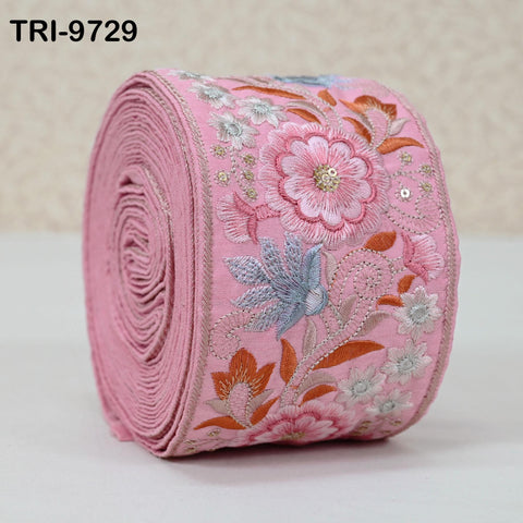 A pink fabric with a floral pattern, featuring a large pink flower and smaller flowers in shades of white and blue.