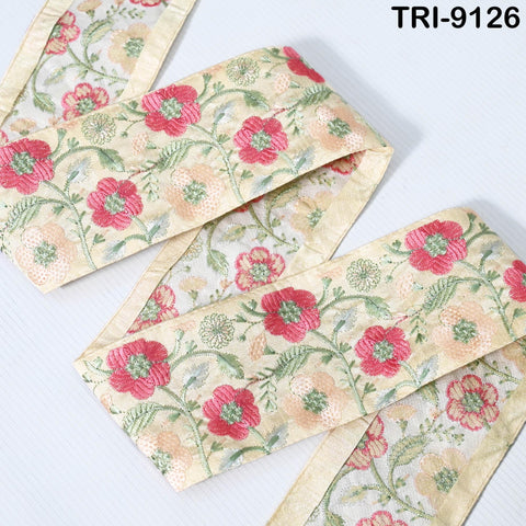 a close-up view of a decorative fabric with a floral pattern in shades of pink and green. The fabric appears to be a ribbon or a piece of cloth with a floral design.