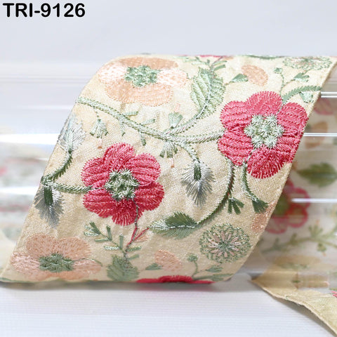a close-up view of a decorative fabric with a floral pattern, featuring red and green flowers and leaves.