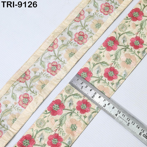 two pieces of fabric with a floral pattern, one with a gold trim and the other with a beige trim. A ruler is placed on the fabric with the gold trim, indicating the size of the fabric.