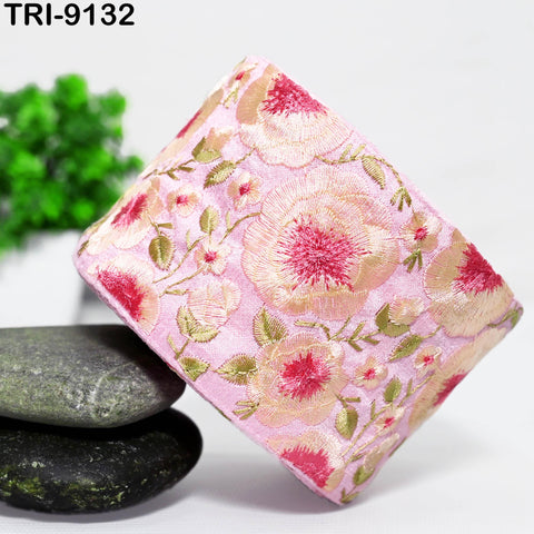 a pink floral fabric with a pink and white floral pattern, placed on a white surface. There are also some green and black stones in the foreground.