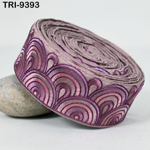 A close-up image of a decorative fabric with a repeating pattern of pink and purple waves or swirls.