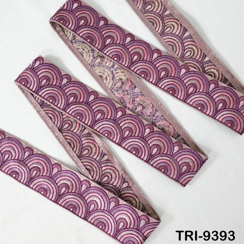 a collection of decorative fabric pieces with a repeating pattern of pink and purple waves or circles. The fabric appears to be made of a shiny material and is arranged in a zigzag pattern.