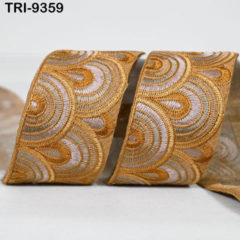two gold-colored ribbons with a repeating pattern of circles and swirls, placed on a white surface.