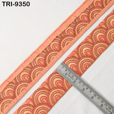 a close-up view of a decorative fabric with a repeating pattern of orange and yellow circles, and a ruler is placed next to it to measure the length of the fabric.