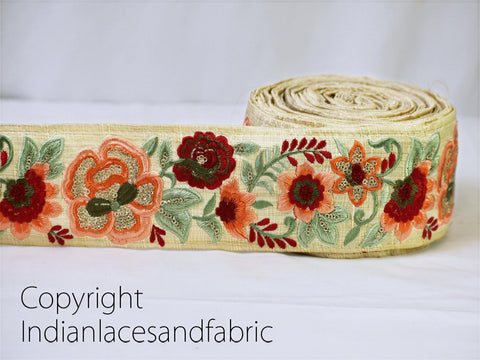 A close-up image of a decorative fabric with a floral pattern, including red, orange, and green flowers, along with leaves and other natural elements.