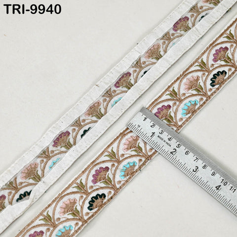 a close-up view of a decorative fabric with a floral pattern, placed next to a ruler for size comparison.