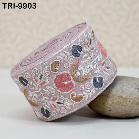 A decorative fabric with a floral pattern is shown, lying on a surface next to a rock.