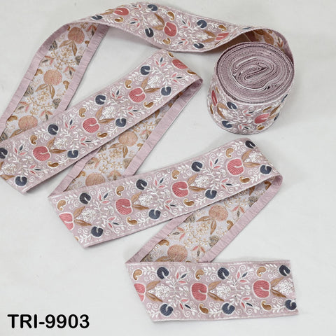 a collection of decorative fabric pieces, including a spool of pink and white floral embroidery and a ribbon with a similar floral pattern.