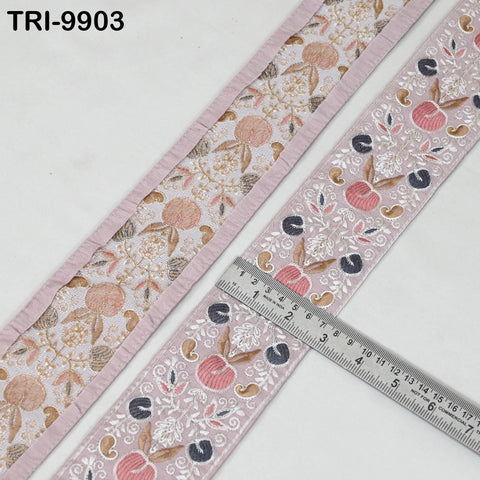 two pieces of fabric with a floral pattern, one with a pink border and the other with a gray border. A ruler is placed on the right side of the fabric, indicating the size or dimensions of the fabric.