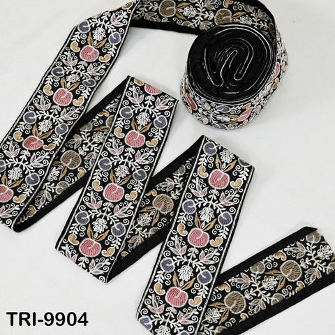 a collection of decorative fabric pieces, including a spool of black and white embroidered fabric and a long piece of fabric with a floral pattern.