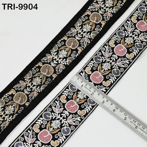 two spools of black and white embroidered fabric with a floral pattern. A ruler is placed on top of the fabric, indicating the size of the spools.