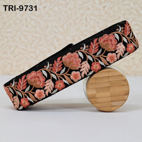 a decorative black fabric with a floral pattern in shades of pink and orange, displayed on a wooden surface.