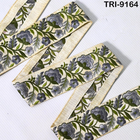 a decorative fabric with a floral pattern in shades of green and blue. The fabric appears to be a decorative trim or ribbon, with a repeating floral design.