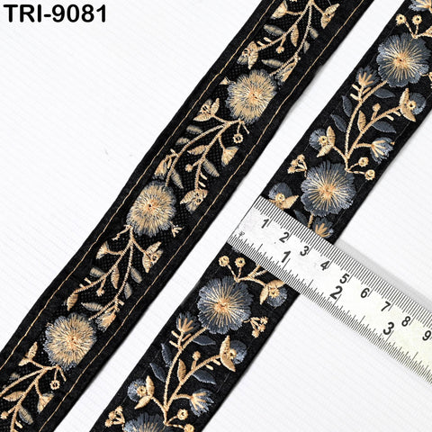 a decorative black and gold embroidered fabric with a ruler placed on top of it, indicating the size of the fabric.