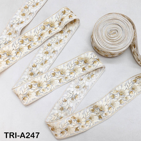 two rolls of white and gold embroidered fabric, with one roll placed on top of the other.