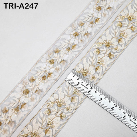 a close-up view of a decorative ribbon with a floral pattern, placed on a white surface. A ruler is visible, indicating the size or dimensions of the ribbon.