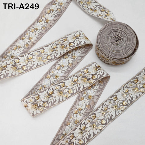 a collection of decorative fabric ribbons with a floral pattern. The ribbons are arranged in a way that they appear to be rolled up or coiled, with one ribbon lying flat on the surface and the others rolled up around it. The ribbons have a light brown color and a white floral pattern, creating a visually appealing and elegant design.