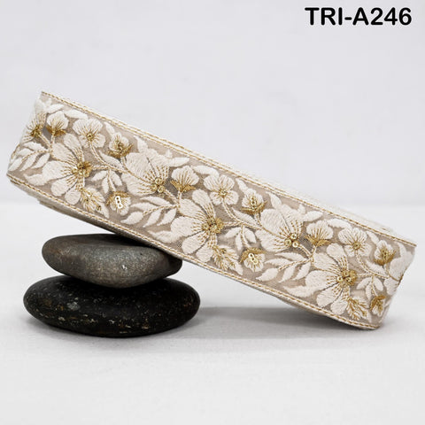 A decorative fabric with a floral pattern is displayed on a white surface, resting on a stack of three rocks.