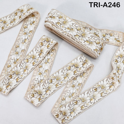 several spools of white and gold embroidered fabric, arranged on a white background.