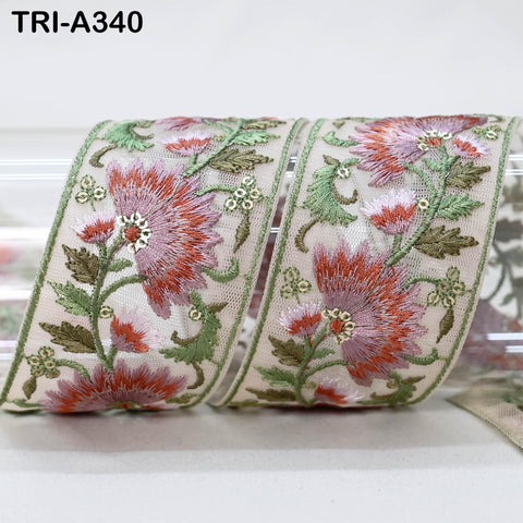 a decorative fabric with a floral pattern, featuring red and green flowers and leaves. The fabric appears to be a decorative ribbon or trim, with a floral motif and a green border.