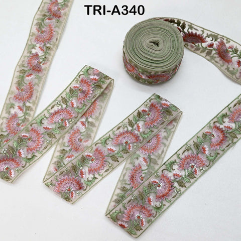 a collection of decorative fabric pieces, including a spool of green thread with a floral pattern and several pieces of fabric with a similar floral design.