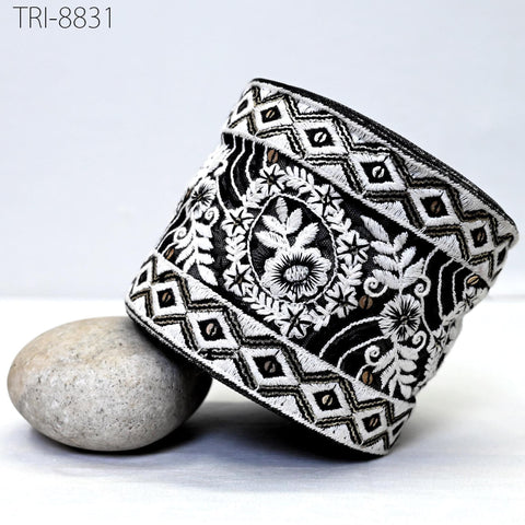 a black and white patterned fabric with a floral design, placed on a white surface next to a gray rock.
